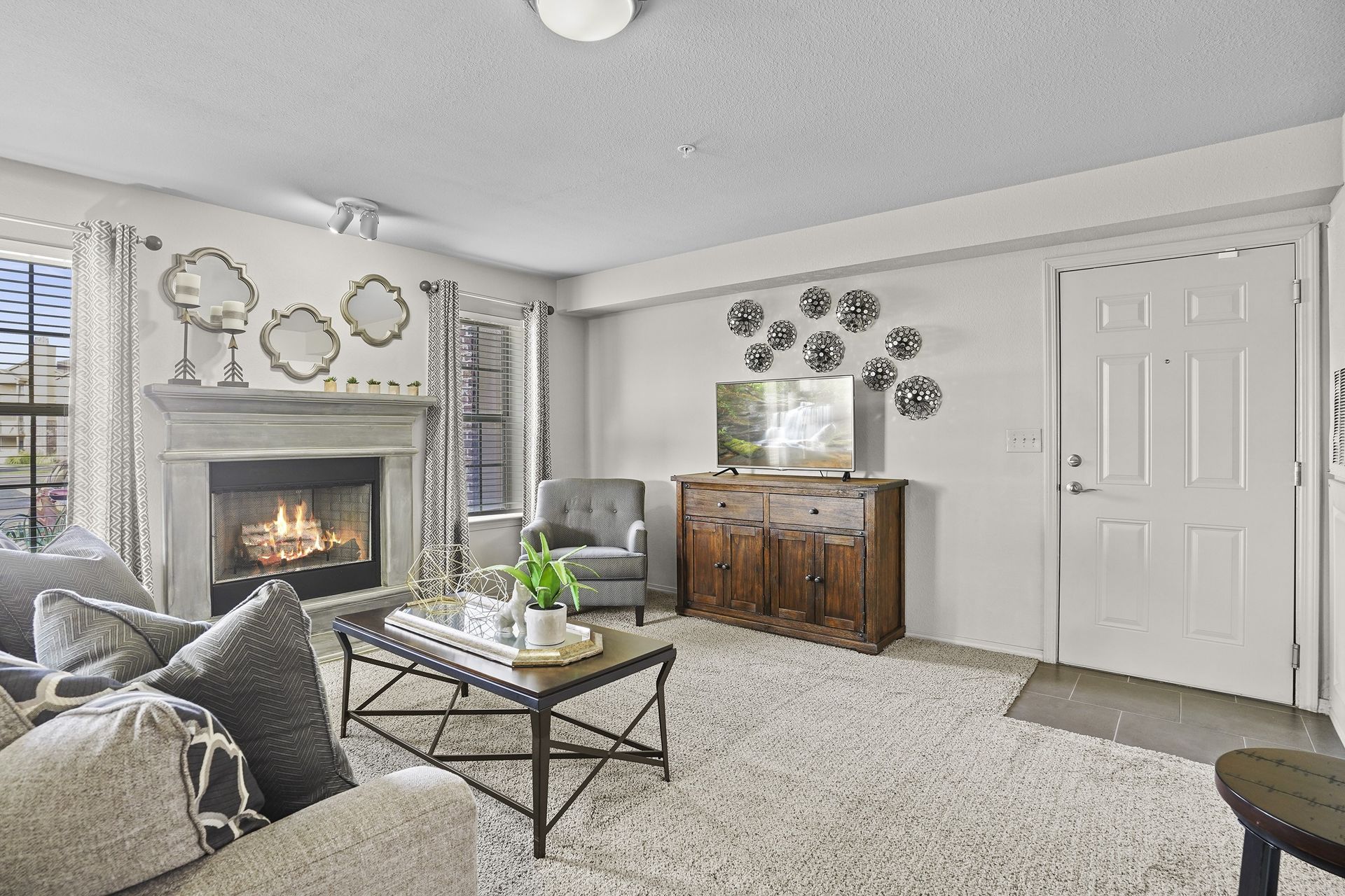 A living room with a fireplace, grey couch, and a coffee table.