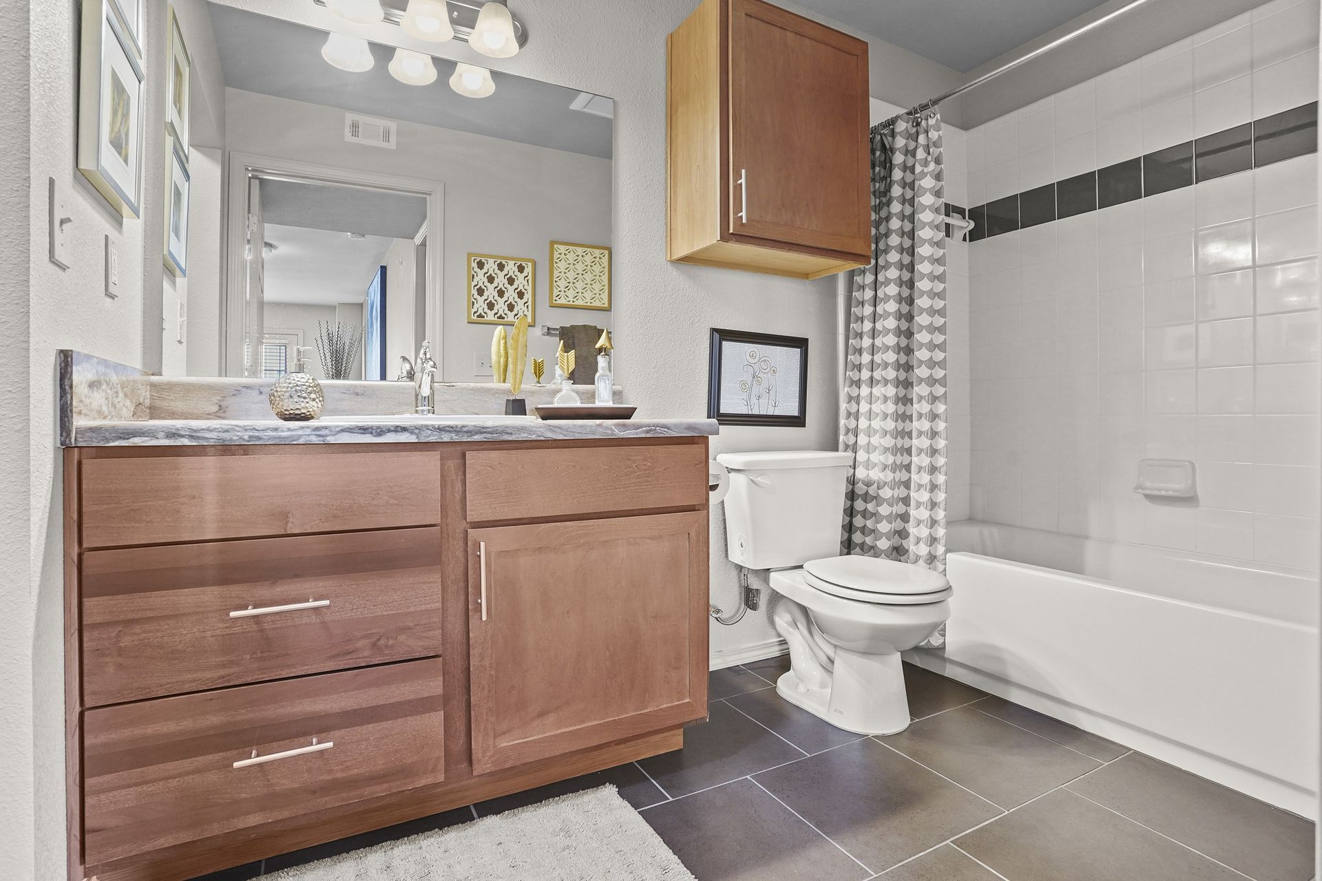 A bathroom with a toilet, sink, and wooden cabinets.