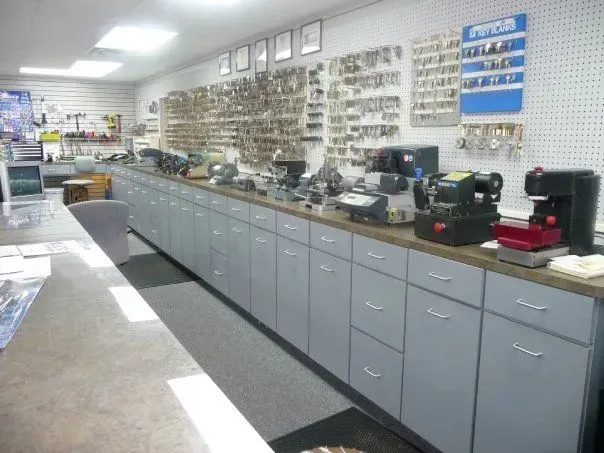 A well-organized locksmith shop with a long counter featuring key-cutting machines.