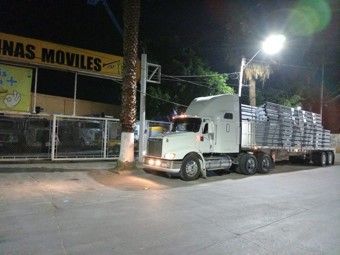 Un camión semirremolque está estacionado al costado de la carretera por la noche.
