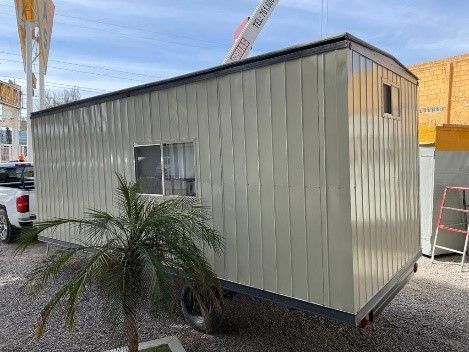 Un pequeño edificio blanco con una palmera delante.