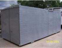 Un gran contenedor gris se encuentra sobre un camino de tierra.