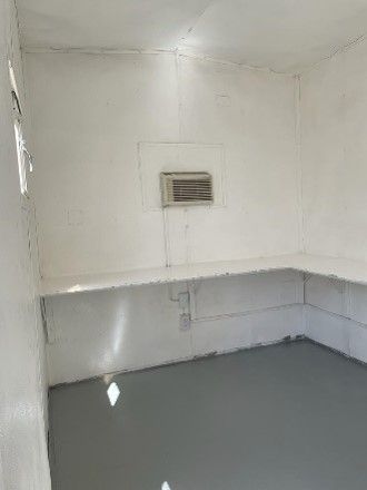 Una habitación con suelo gris, paredes blancas y una ventana.