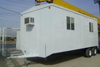 Un remolque blanco con dos ruedas está estacionado al costado de la carretera.