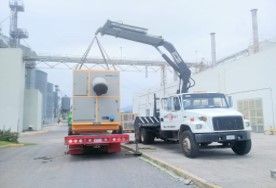Un camión con una grúa acoplada transporta una caja grande.