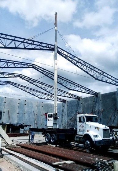 Un camión blanco con una cruz roja en el frente está estacionado frente a un edificio en construcción.