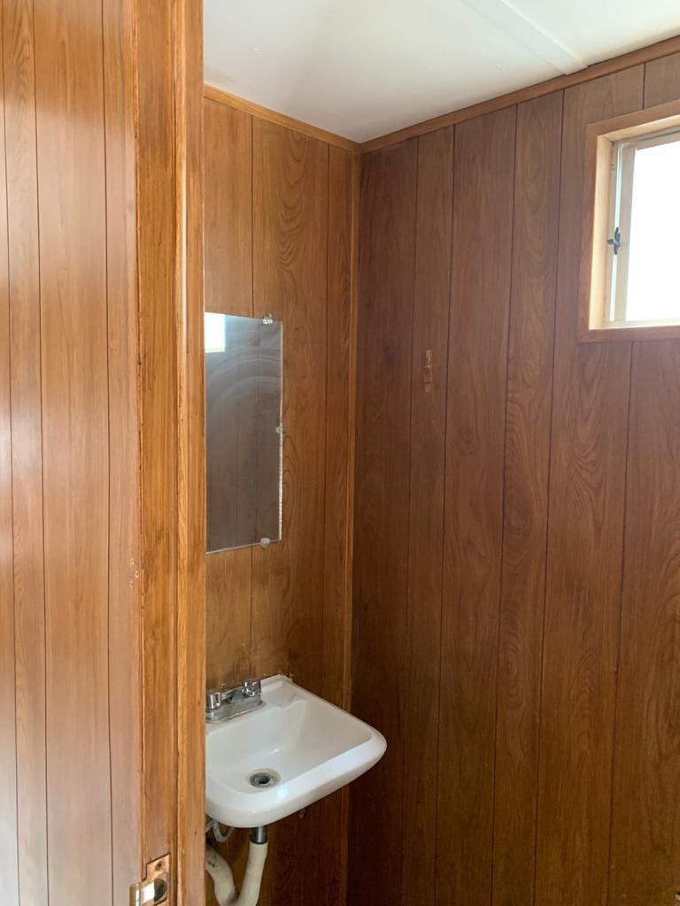 Un baño con paneles de madera y lavabo y espejo.