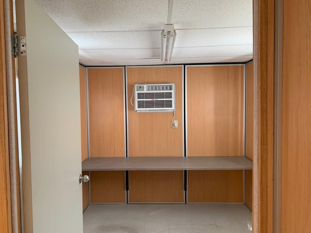 Una habitación vacía con paneles de madera y un ventilador de techo.