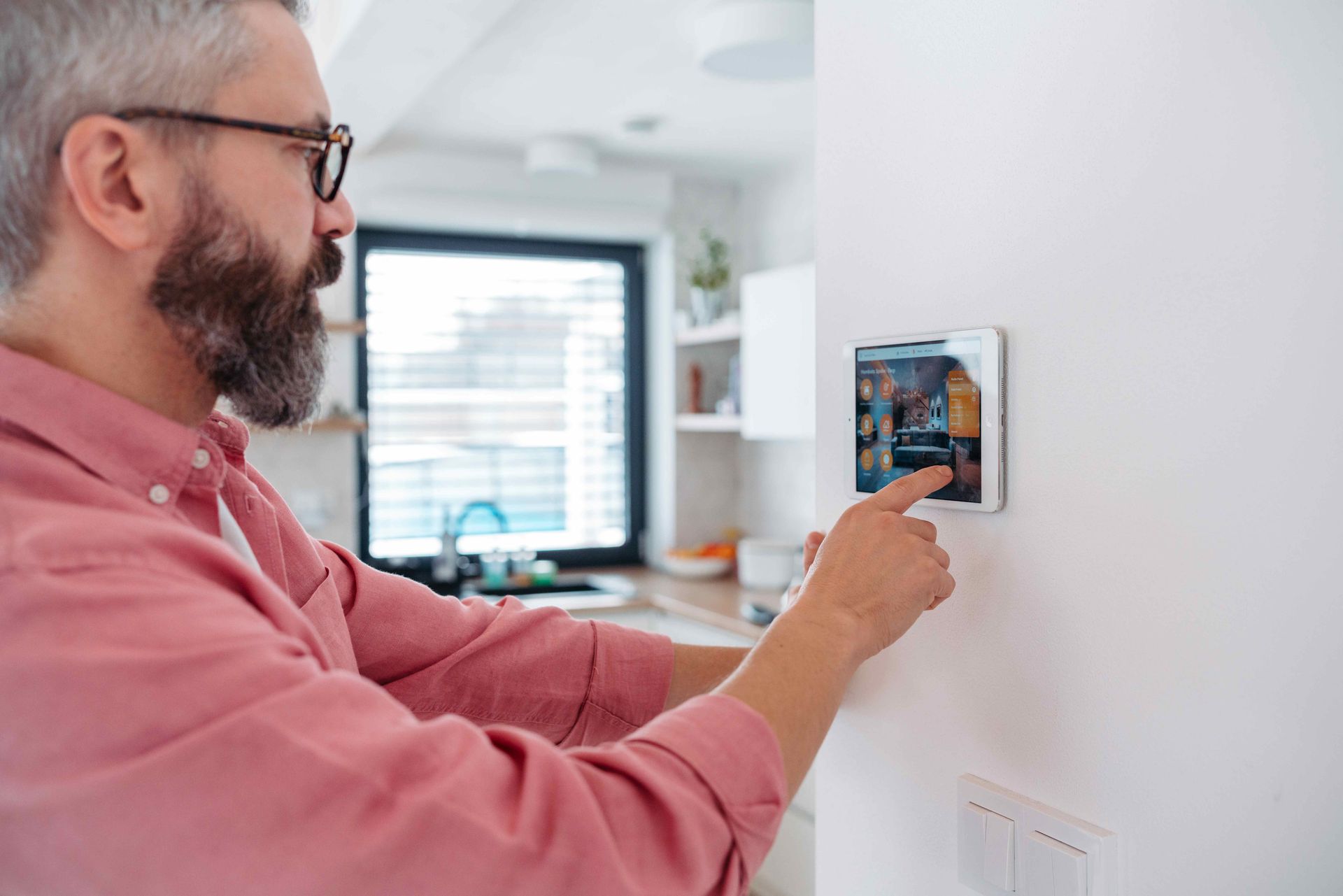 Man adjusting a wall thermostat in a bright home interior