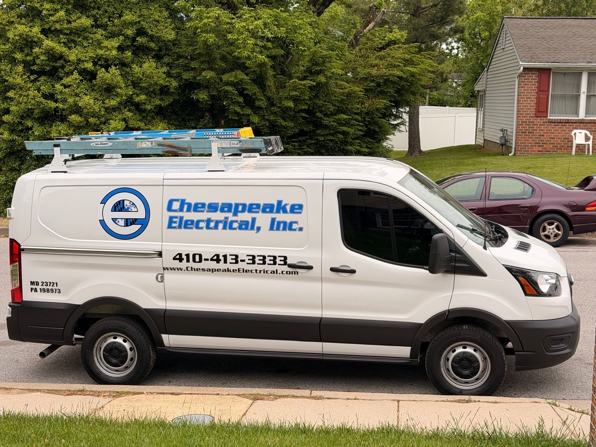 White electrician van parked outside a modern office building
