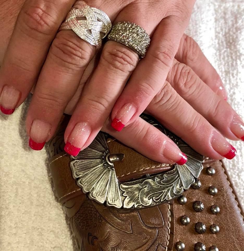 A close up of a woman 's hands with red nails and rings