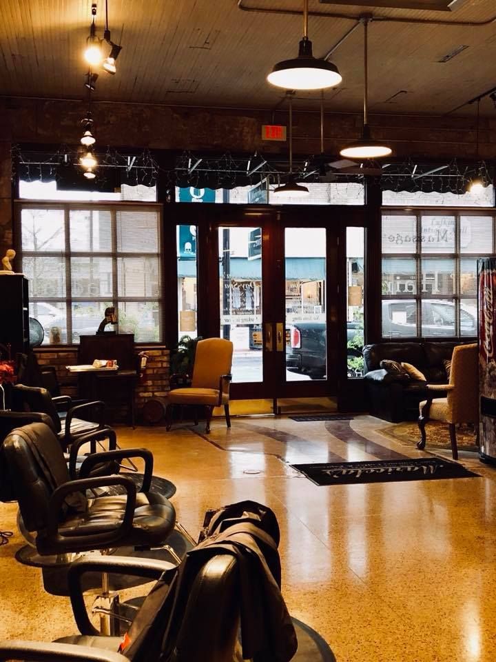 A dog is sitting in a chair in a barber shop.