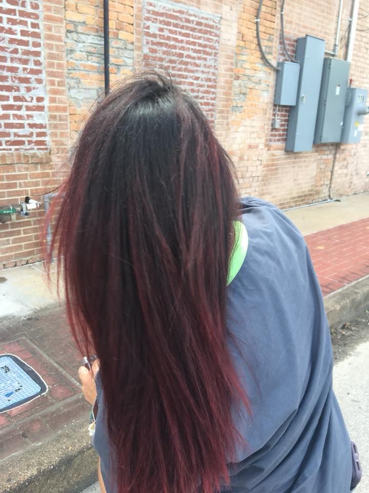 A woman with long red hair is standing in front of a brick building.