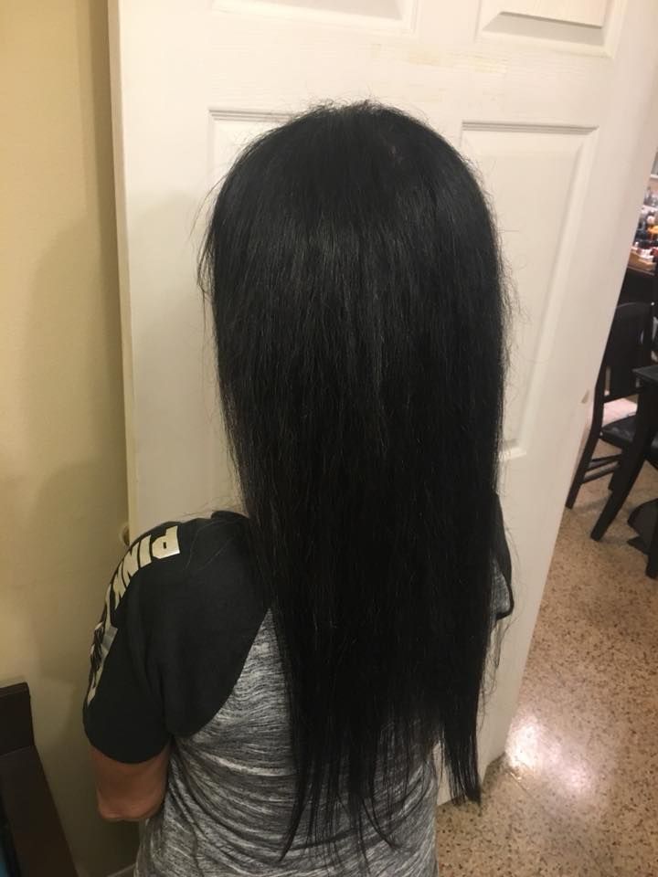 A woman with long black hair is standing in front of a door.