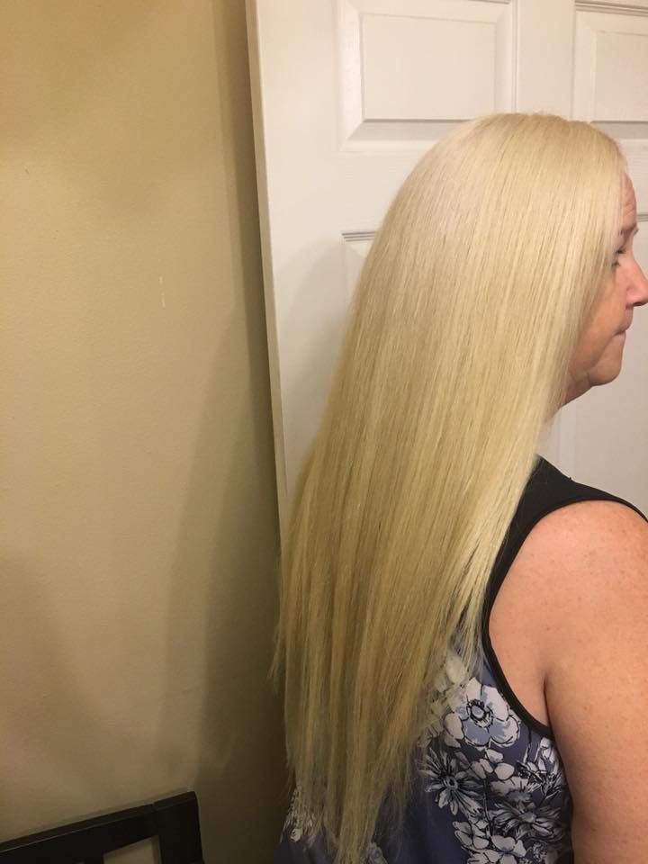 A woman with long blonde hair is standing in front of a door.