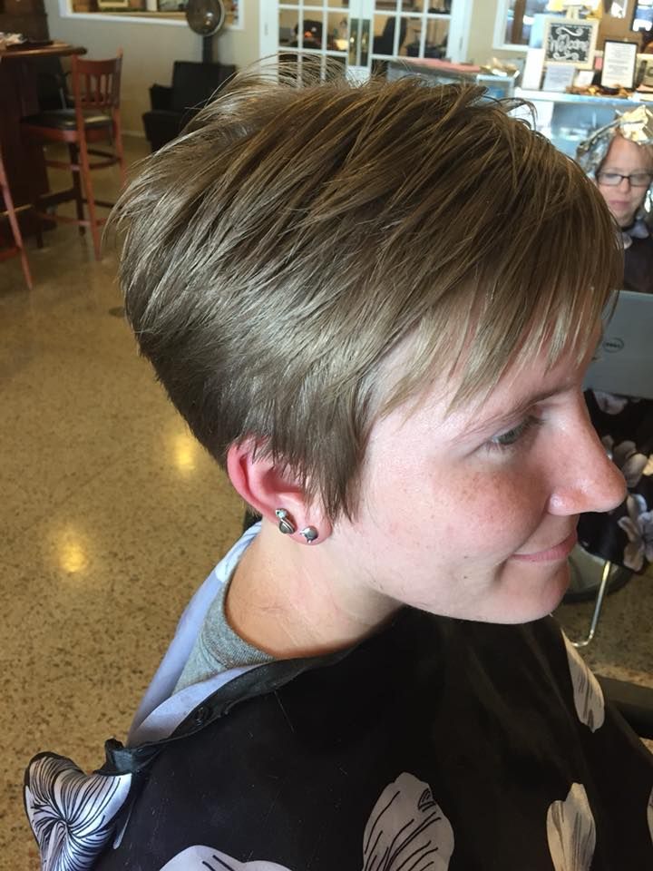 A woman with short hair and earrings is sitting in a salon.
