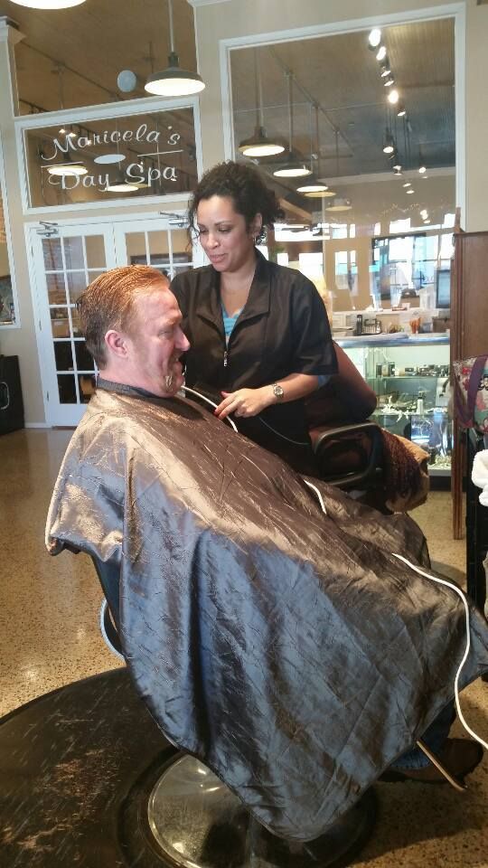 A man is getting his hair cut by a woman in a barber shop.