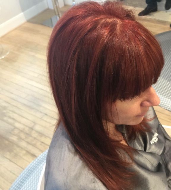 A woman with red hair is getting her hair cut