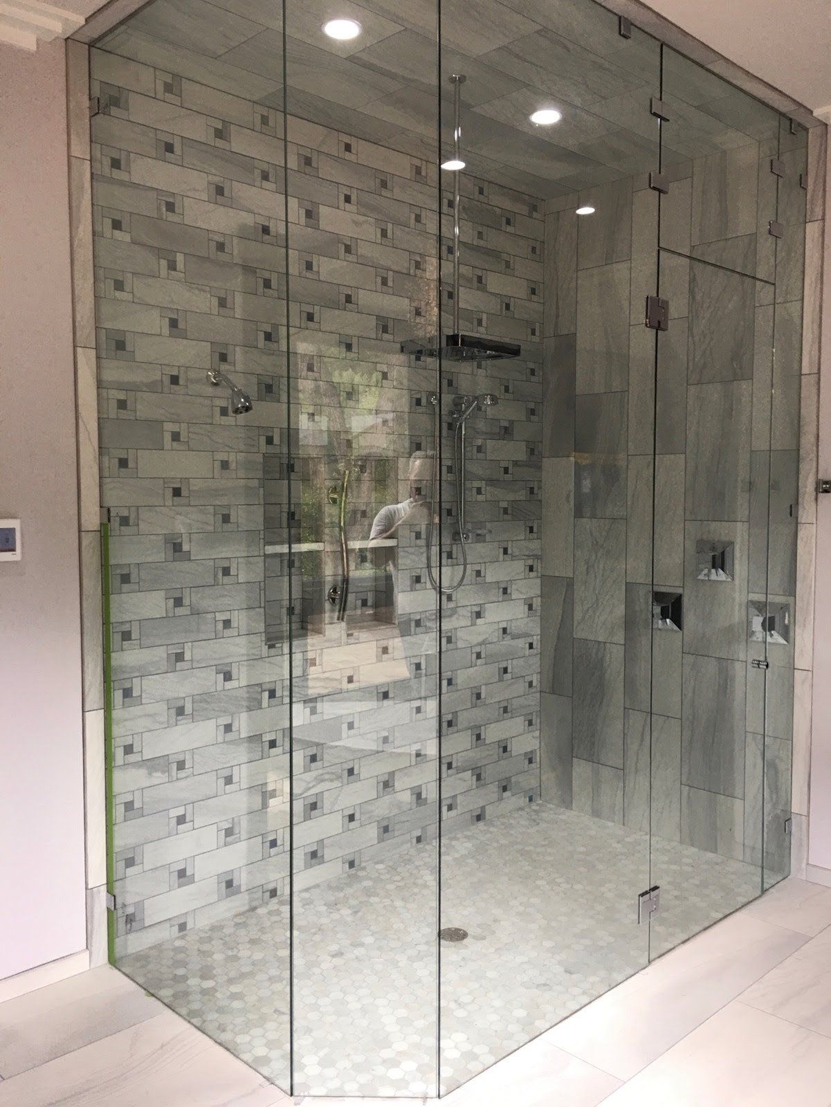 A bathroom with a walk in shower with a glass door.
