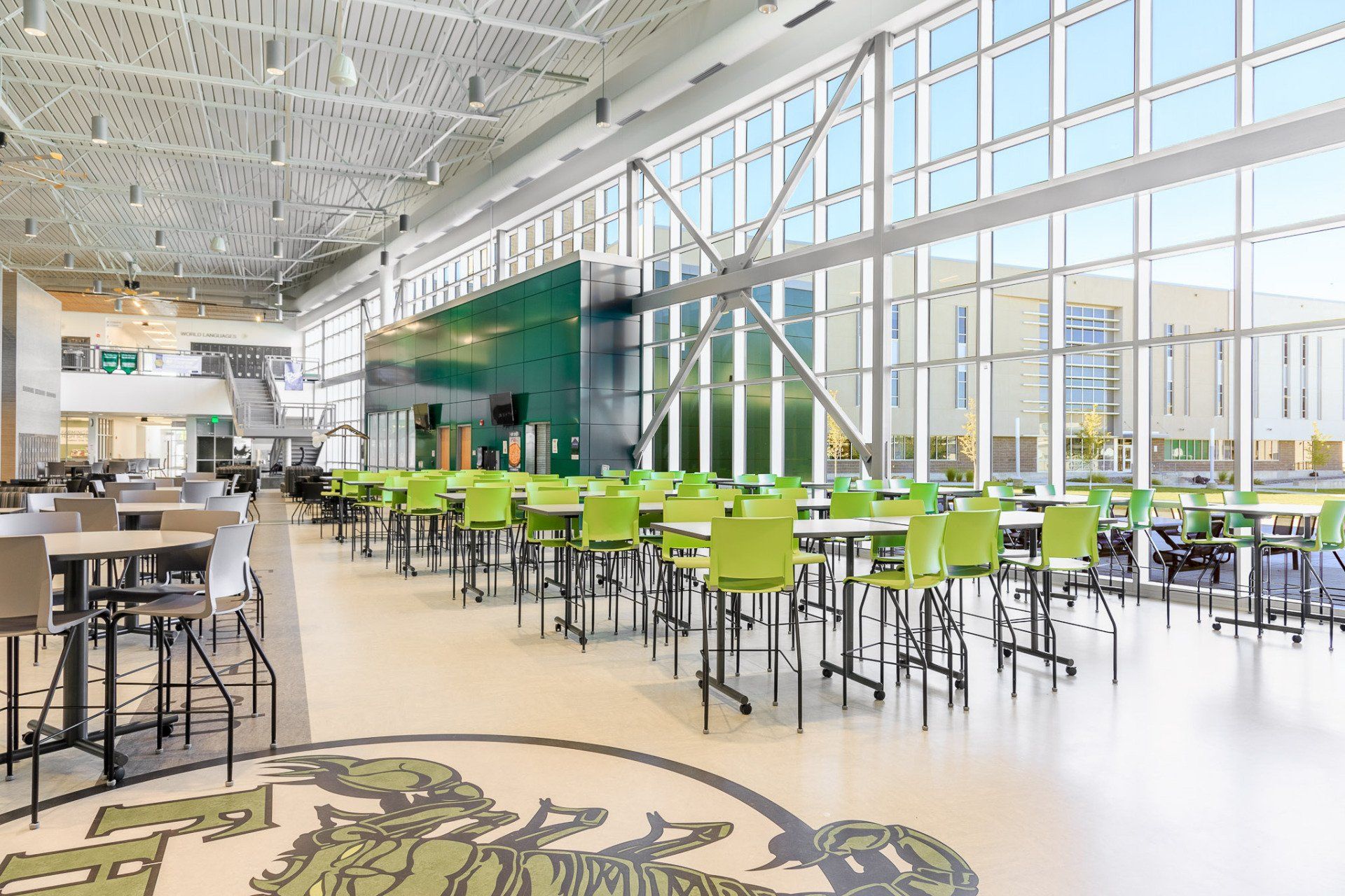 a school cafeteria with tables and chairs with huge windows installed by Sun Glass