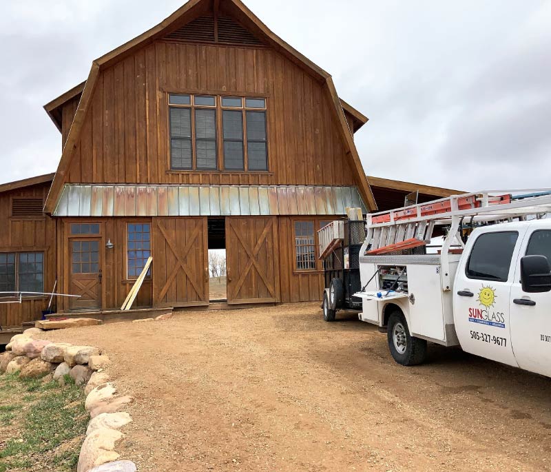 a white sunglass truck is parked in front of a barn