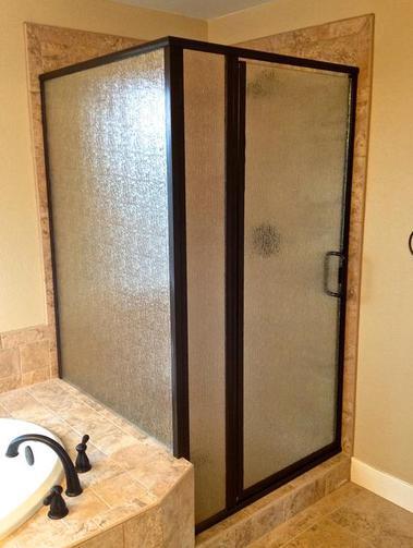 a bathroom with a walk in shower and custom shower glass made by Sun Glass