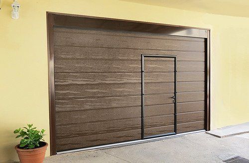 una porta del garage marrone con una porta e un vaso di fiori accanto a essa .