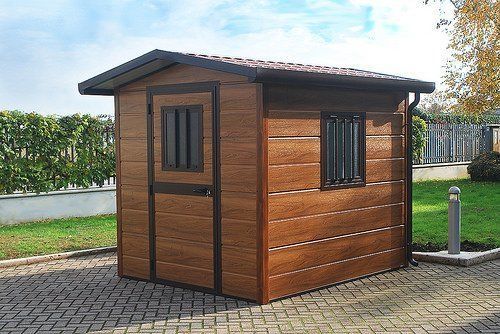 un piccolo capannone in legno con una finestra è parcheggiato su un marciapiede .