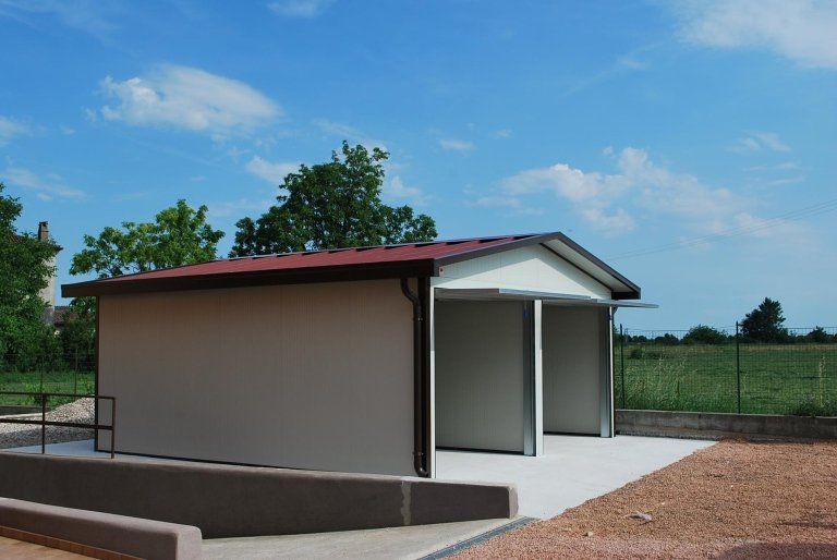 un piccolo edificio con un tetto rosso è in cima a un campo .