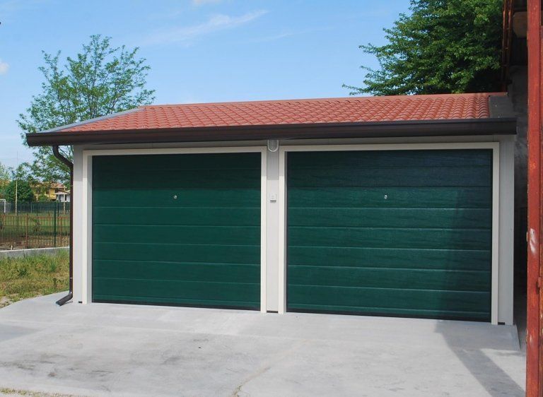 un garage con due porte verdi e un tetto rosso
