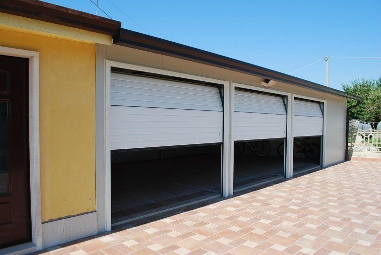 un garage con tre porte scorrevoli bianche e una porta marrone .