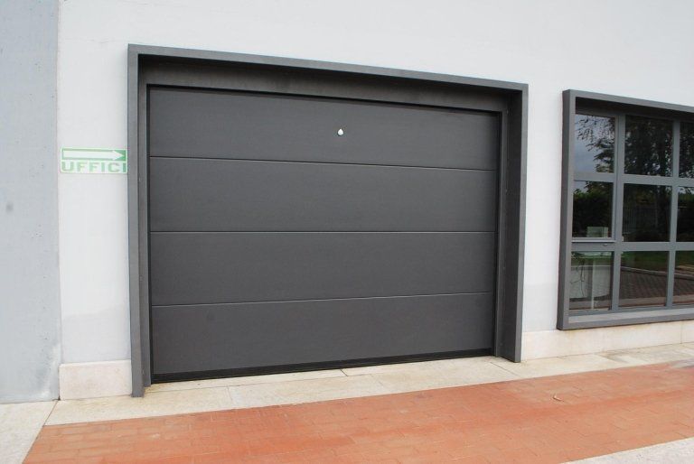 un edificio bianco con una porta da garage nera e una finestra .