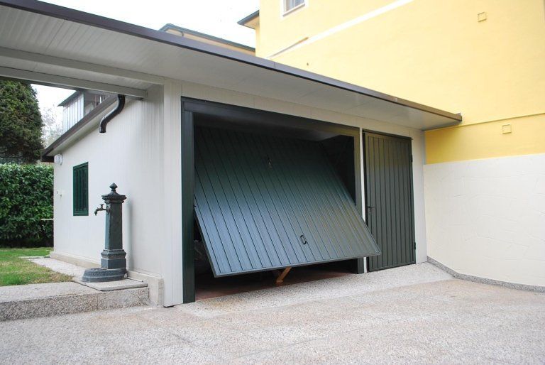 una porta del garage è aperta e si trova accanto a un edificio giallo