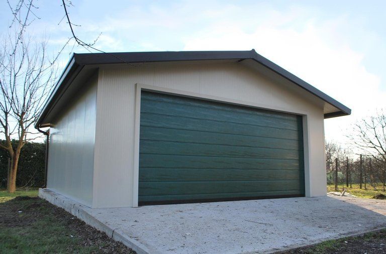 un garage bianco con una porta verde e un tetto marrone
