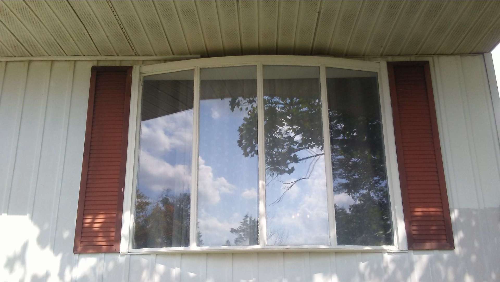 A large window with red shutters on a white house