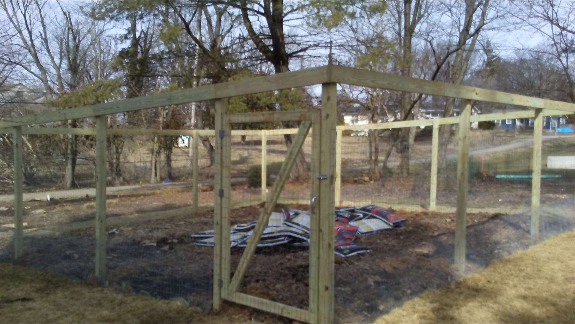 A wooden fence is being built in a yard with trees in the background.