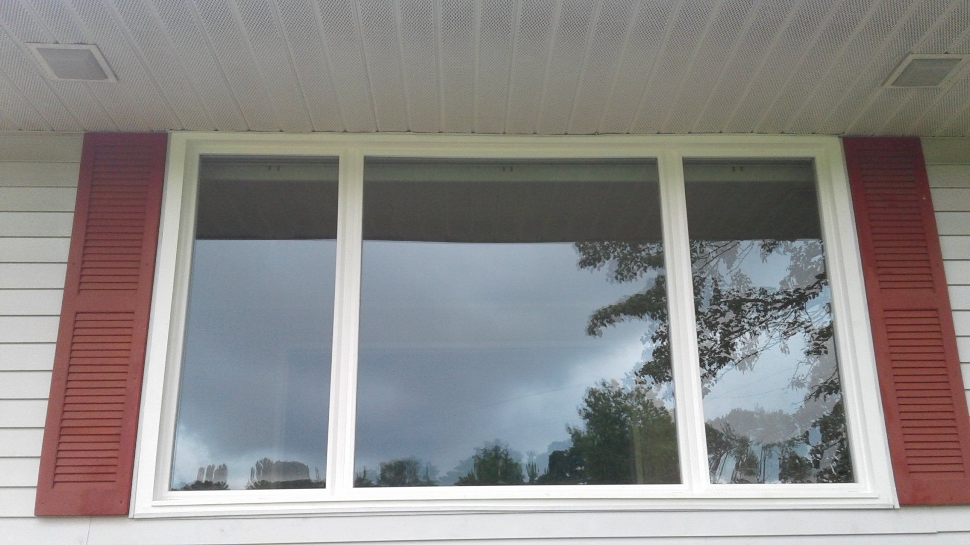 A white window with red shutters on a white house