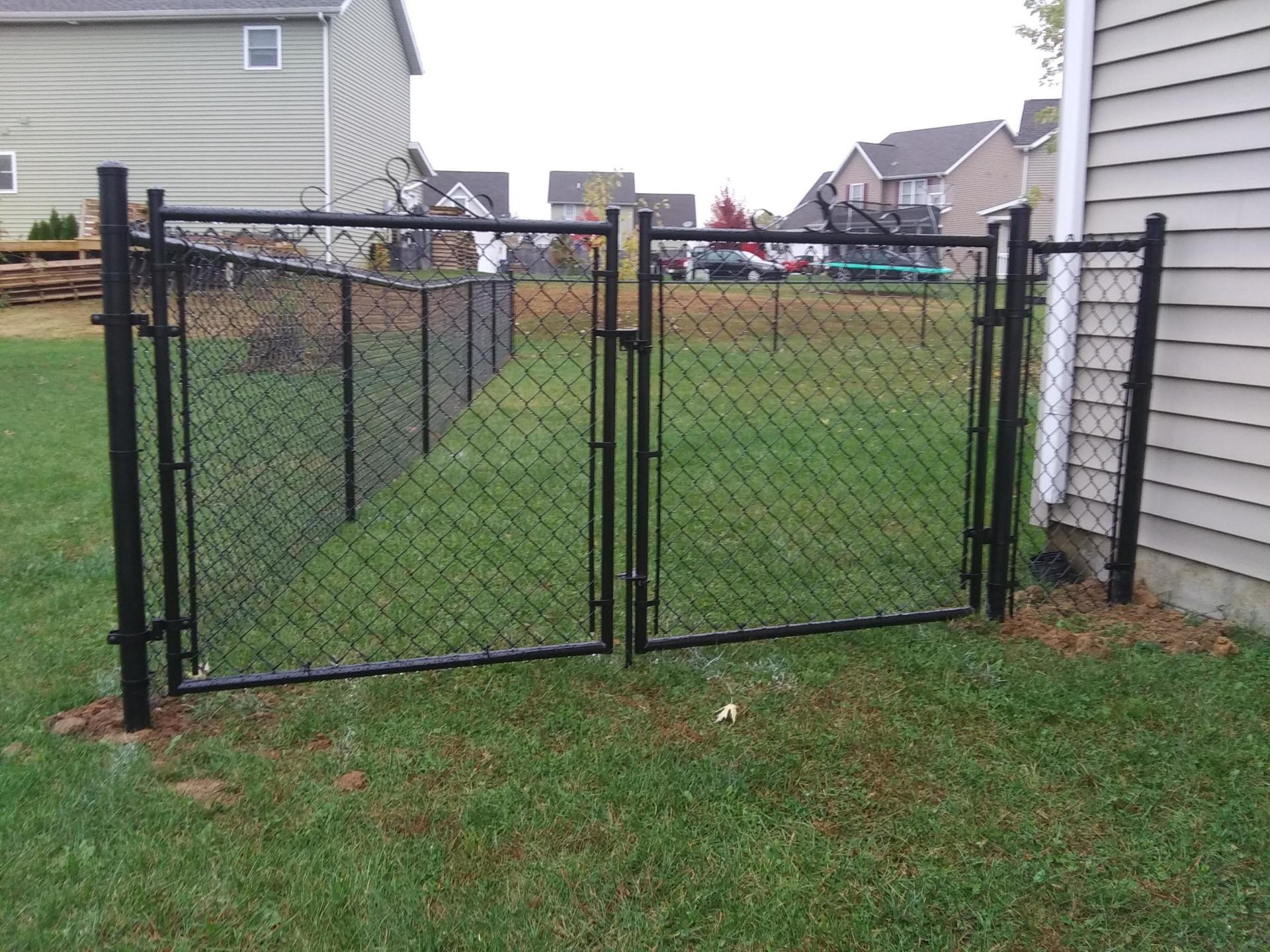 A chain link fence with a gate in the backyard of a house