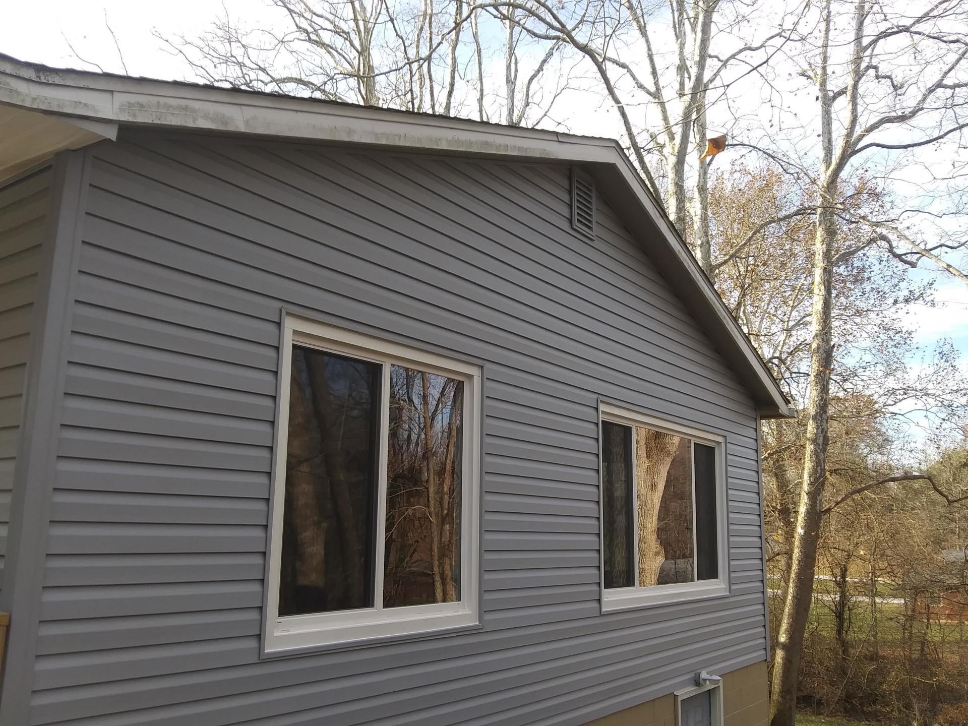 A gray house with a lot of windows and trees in the background.