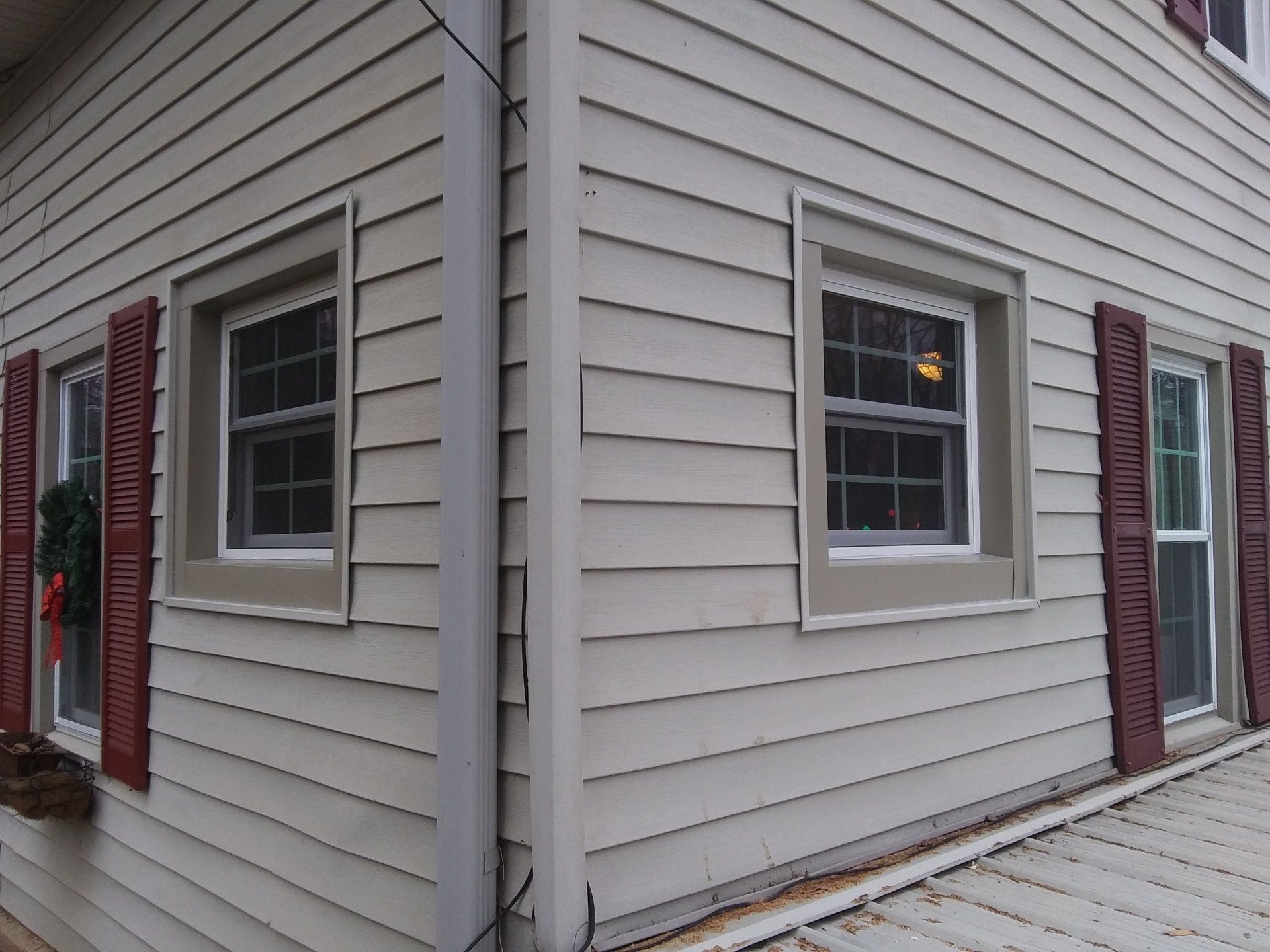 The corner of a house with two windows and red shutters
