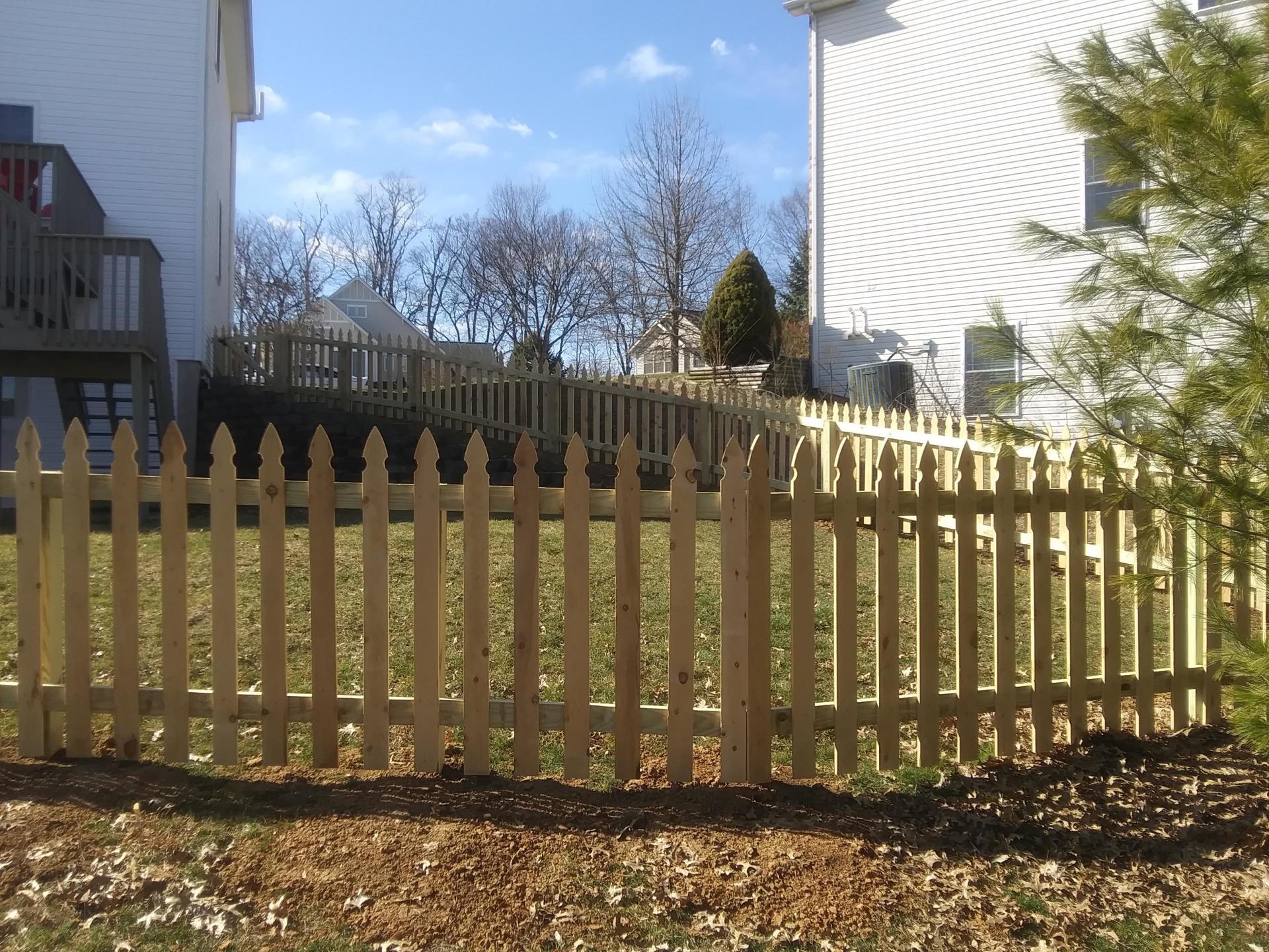 A wooden picket fence in front of a white house