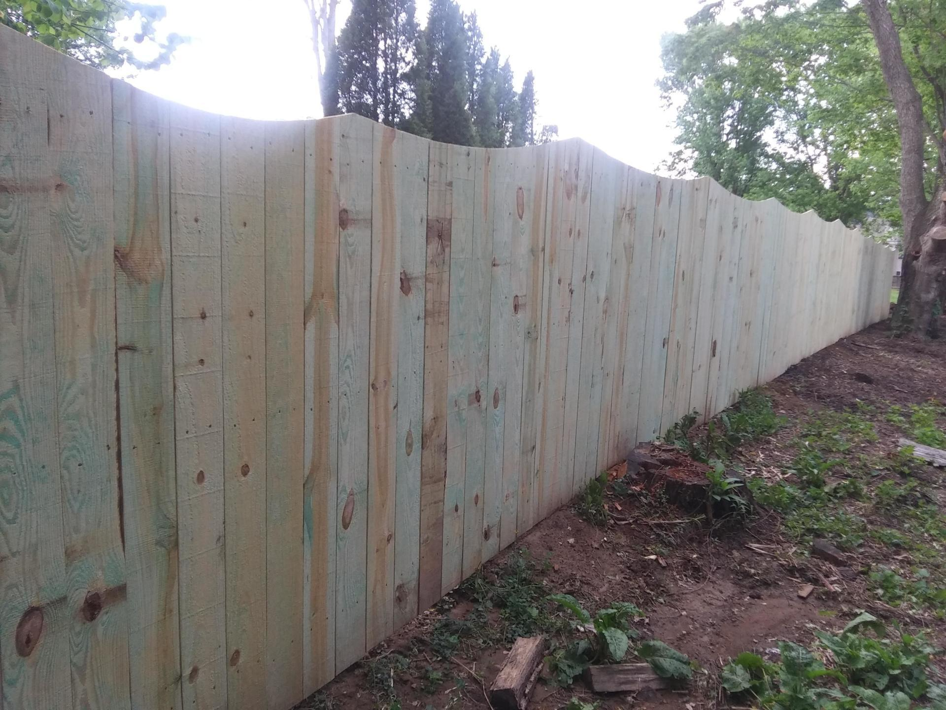 A long wooden fence is surrounded by trees and grass.