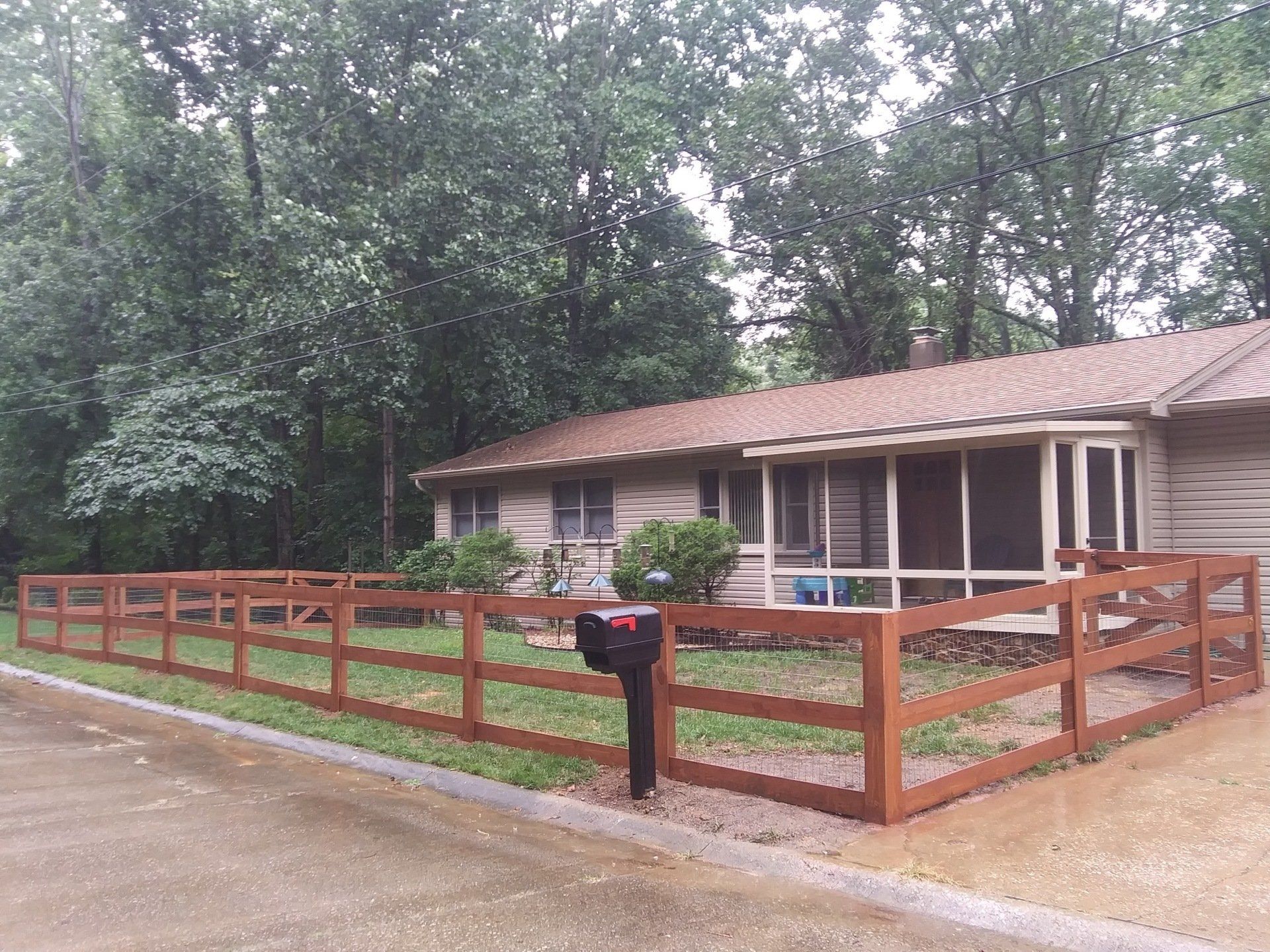 A house with a wooden fence and a mailbox in front of it
