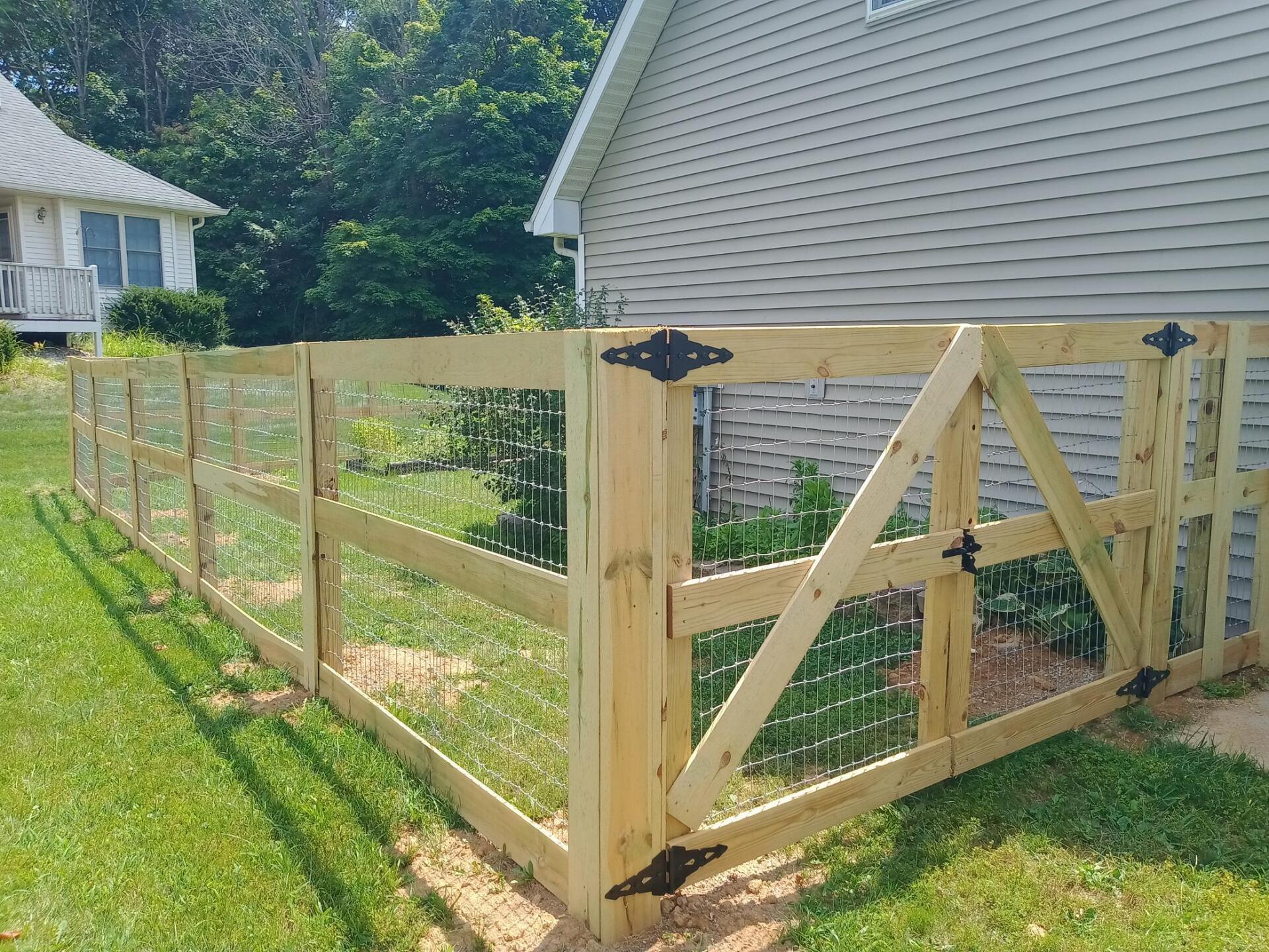 A wooden fence with a gate is in front of a house.