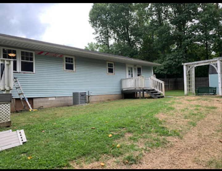 The backyard of a house with a ladder in the grass