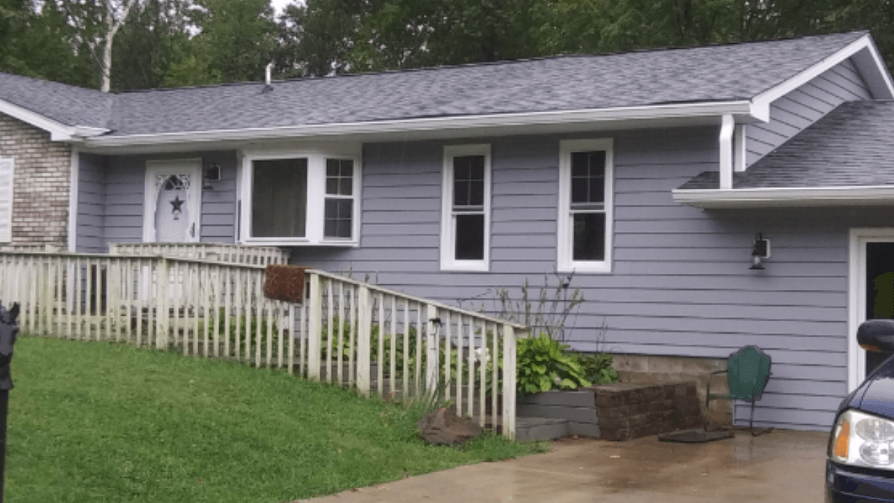 A gray house with a black truck parked in front of it.