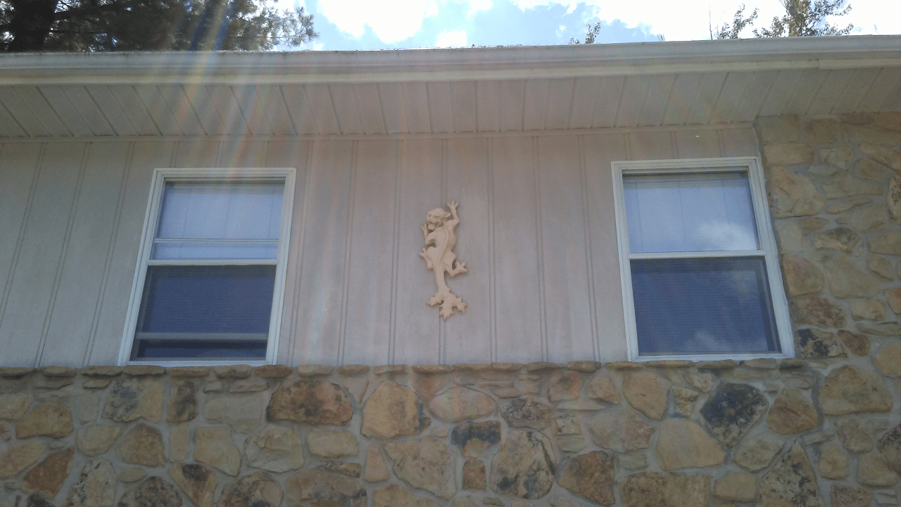 A house with two windows and a statue on the side of it.