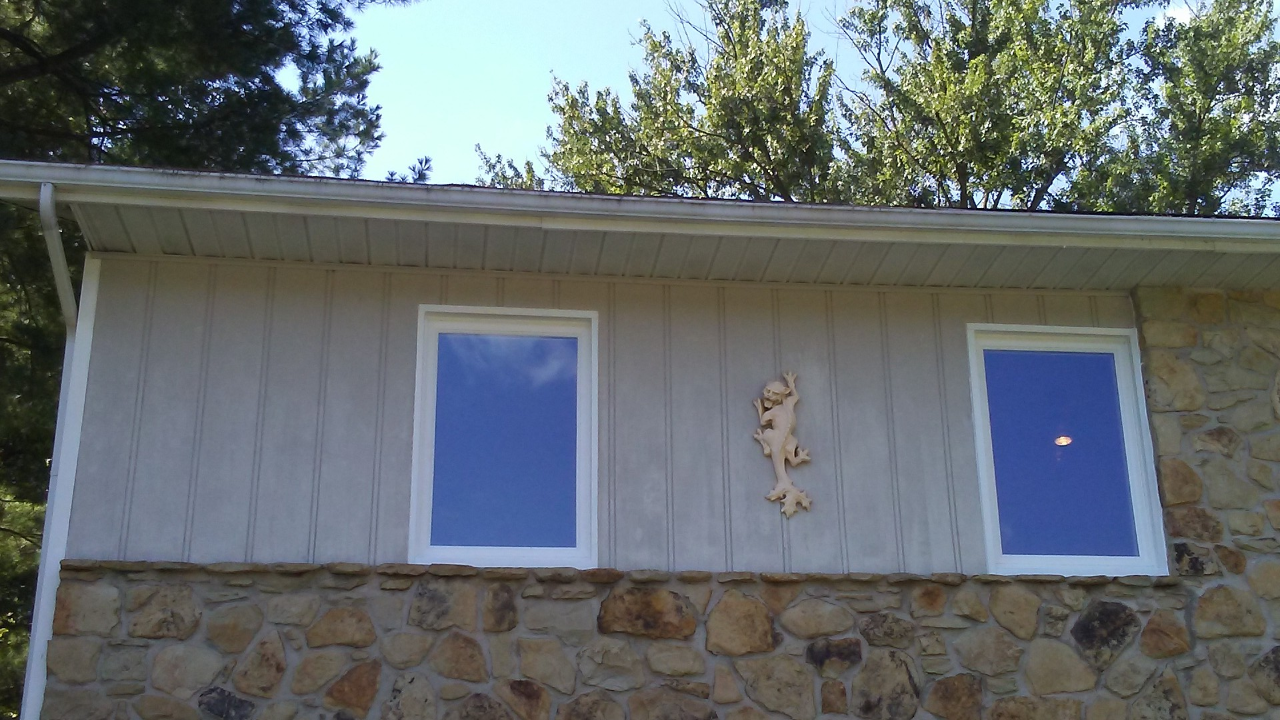 There are two windows on the side of a house.