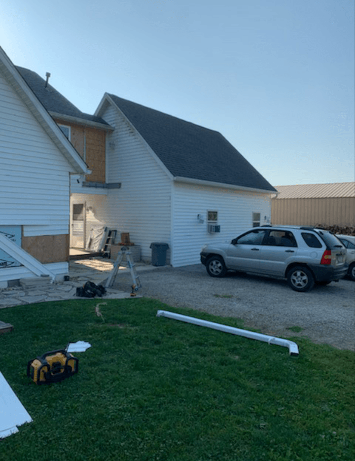A car is parked in front of a white house.