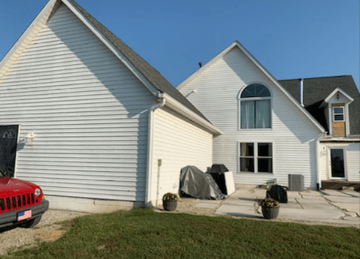 A red jeep is parked in front of a white house